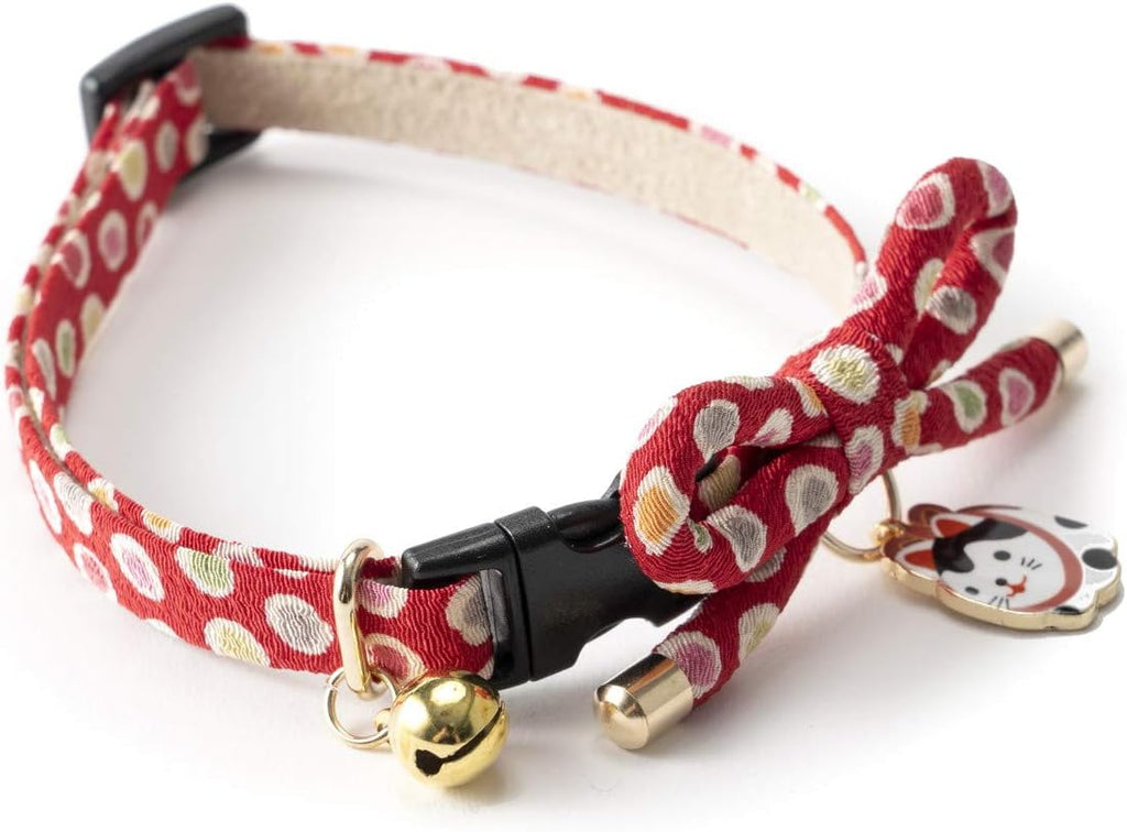 Close up of traditional Japanese hariko paper mache cat charm on red collar