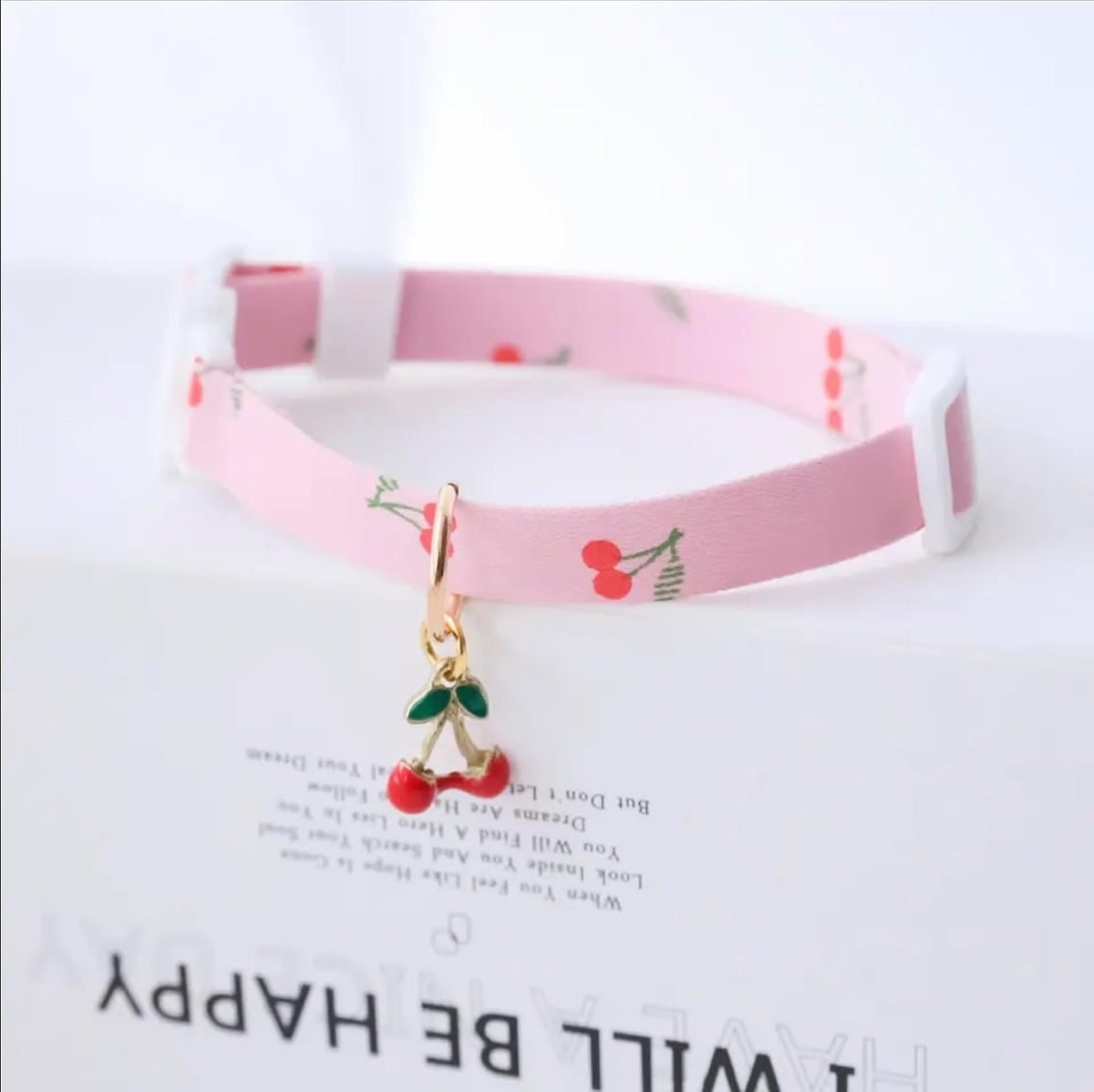 Close up of decorative kitty and cherry charms on matching feline safety collars