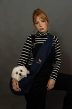 Small dog being carried in Noah and Paw denim sling