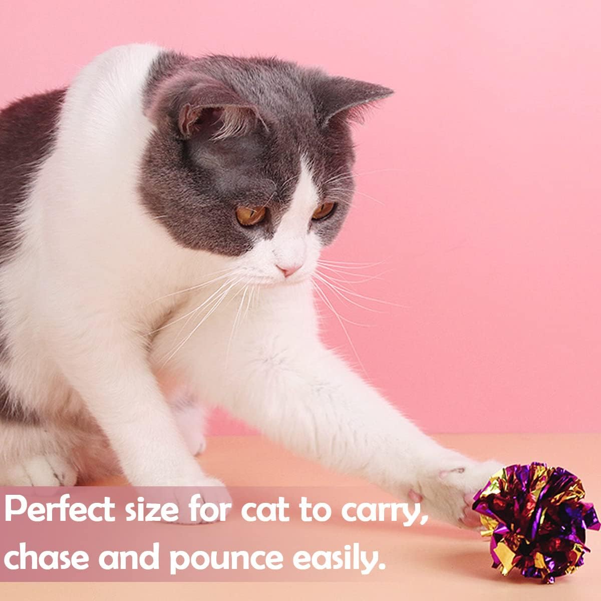 An adult cat pouncing on a bright blue pet show crinkle paper toy ball in a living room