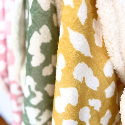 Reversible cozy cat blanket laid flat on a living room sofa for furniture protection.