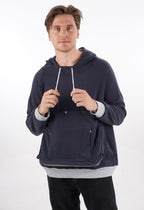 Side angle of a person wearing the navy blue unisex hoodie with a small puppy tucked inside.