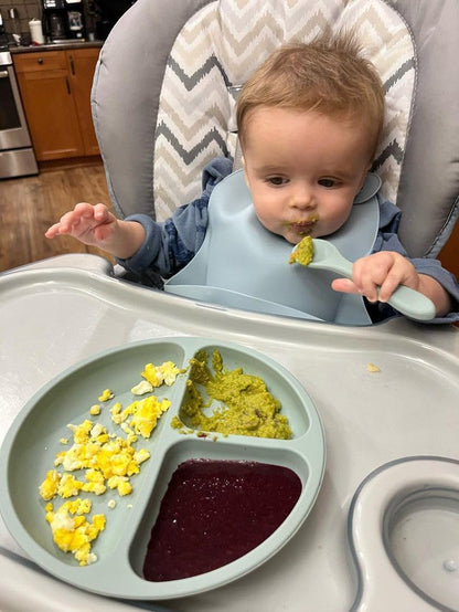 Waterproof stain resistant silicone baby bib rolled up compactly for travel and easy storage.