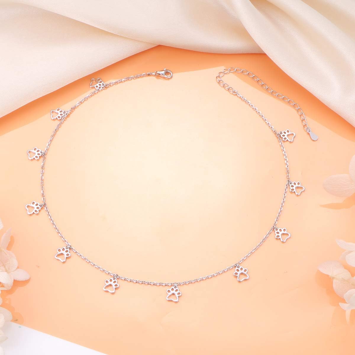 Model wearing the minimalist animal paw print silver statement necklace adjusted to a tight choker length.