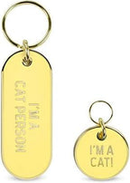 Close up of the teal cat collar tag with gold lettering and charm ring.