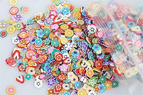 Close up view of miniature five millimeter polymer clay fruit and flower charms spread out for DIY nail art and resin crafting