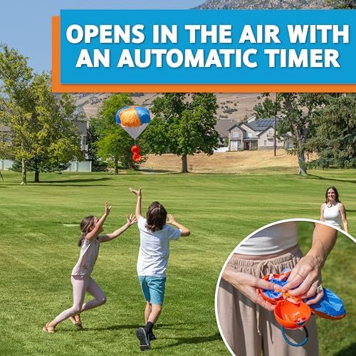 Kids and adults playing with the Djubi slingshot parachute game in a spacious green park.