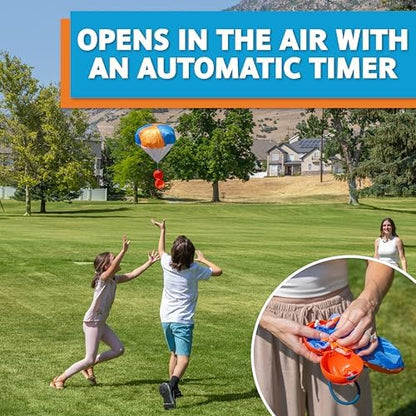 Kids and adults playing with the Djubi slingshot parachute game in a spacious green park.