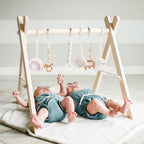 Mallify wooden baby gym front view showcasing the natural pine wood A-frame and hanging sensory toys.