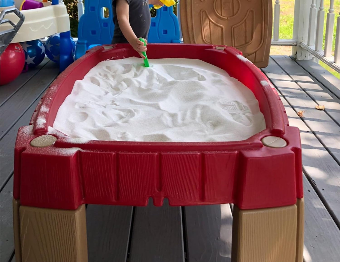 Children playing with clean white non toxic sensory sand in an outdoor sandbox