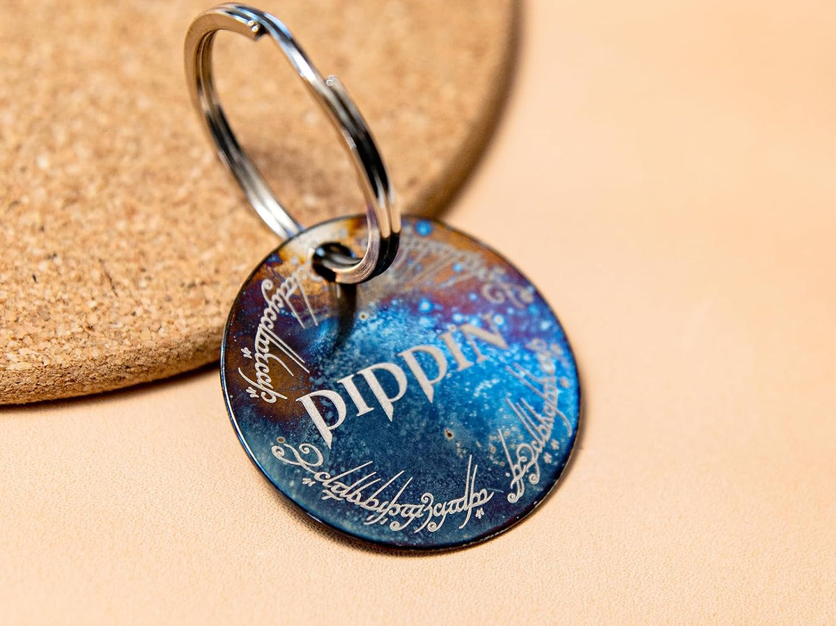 Flame fired distressed metal cat collar ID tag displaying the personalized cursive font.