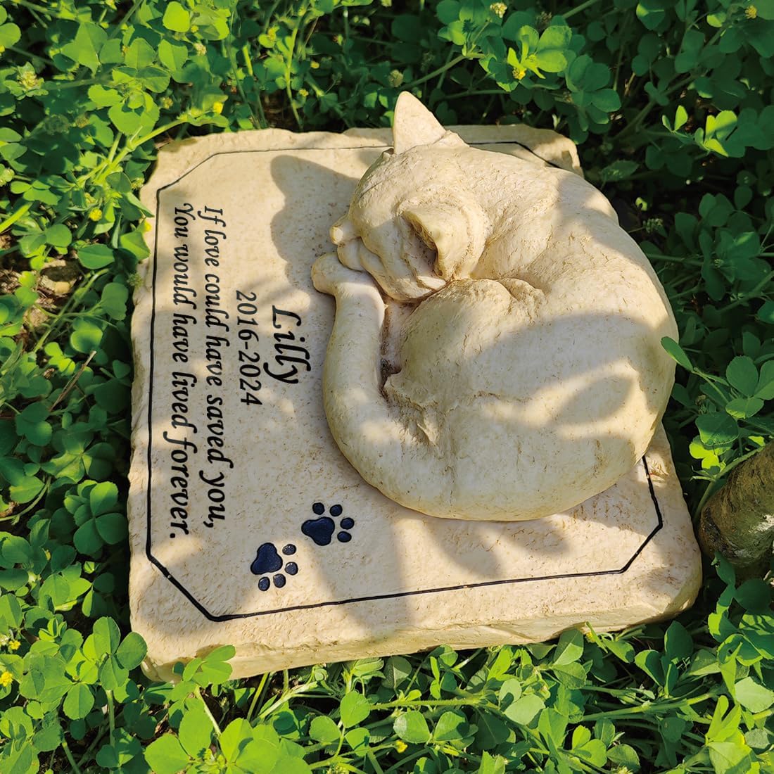Outdoor cat memorial monument displayed under garden foliage.