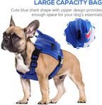 Small dog wearing blue shark backpack harness on walk