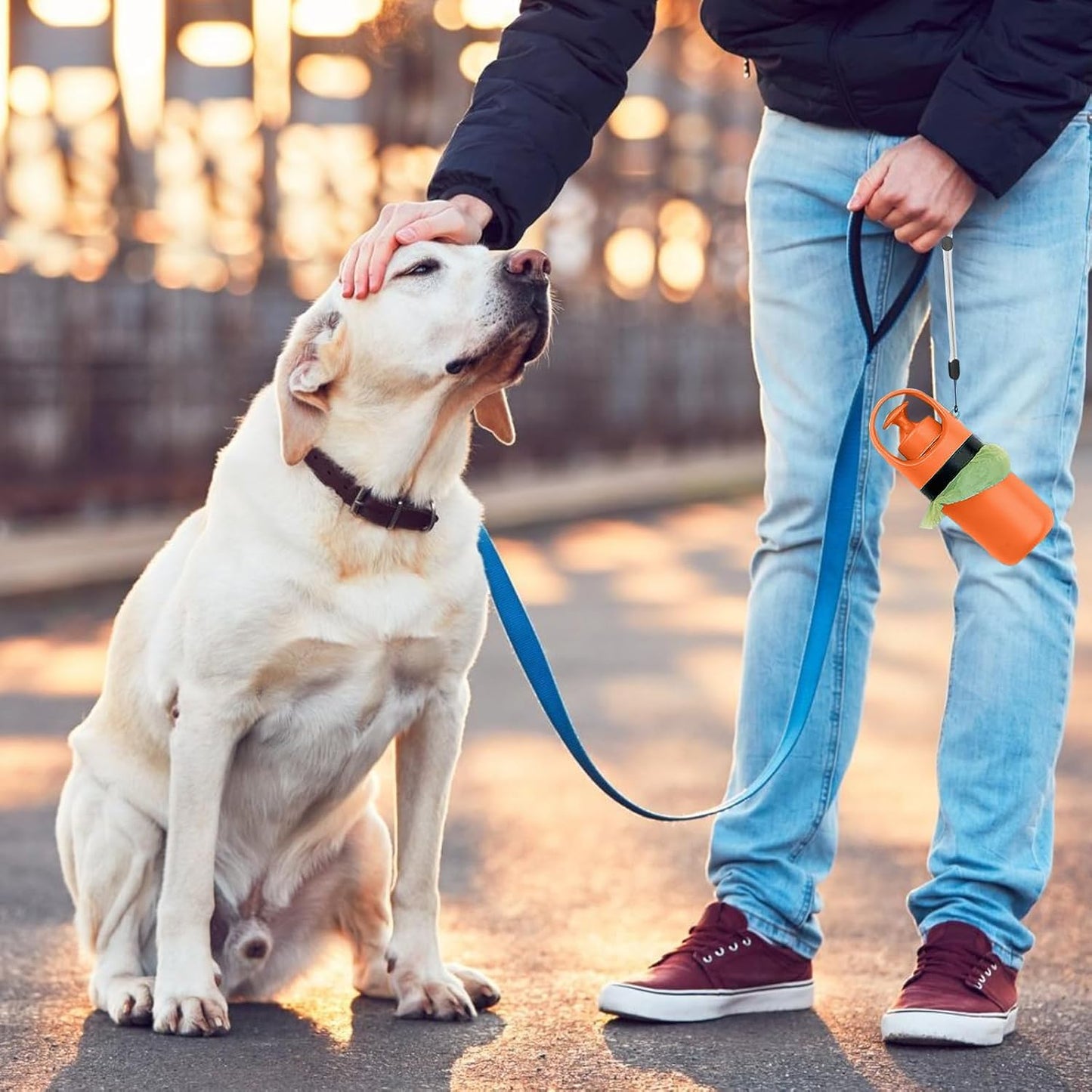 Handheld dog waste clean-up tool with integrated bag attachment showing one-handed operation mechanism.