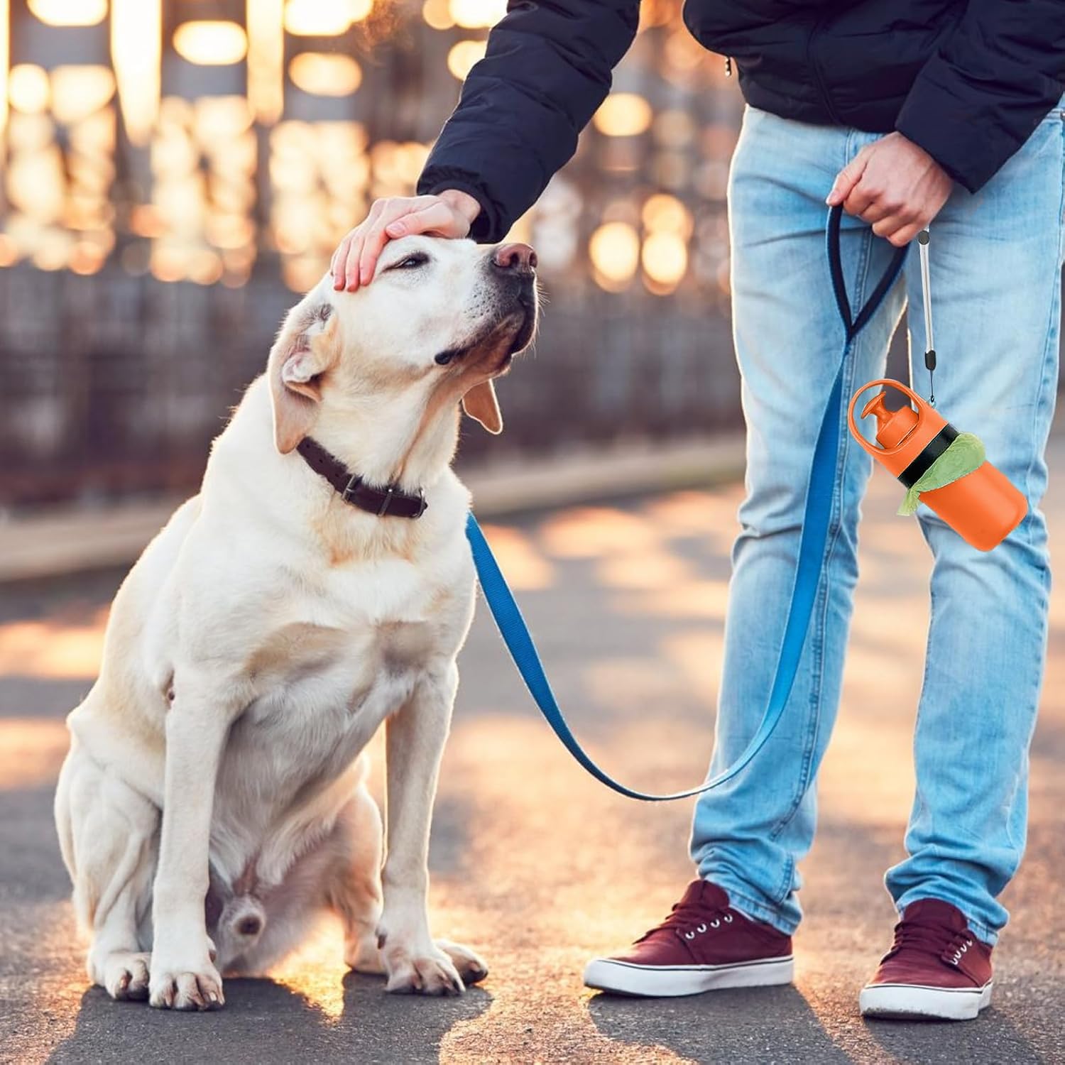 Handheld dog waste clean-up tool with integrated bag attachment showing one-handed operation mechanism.