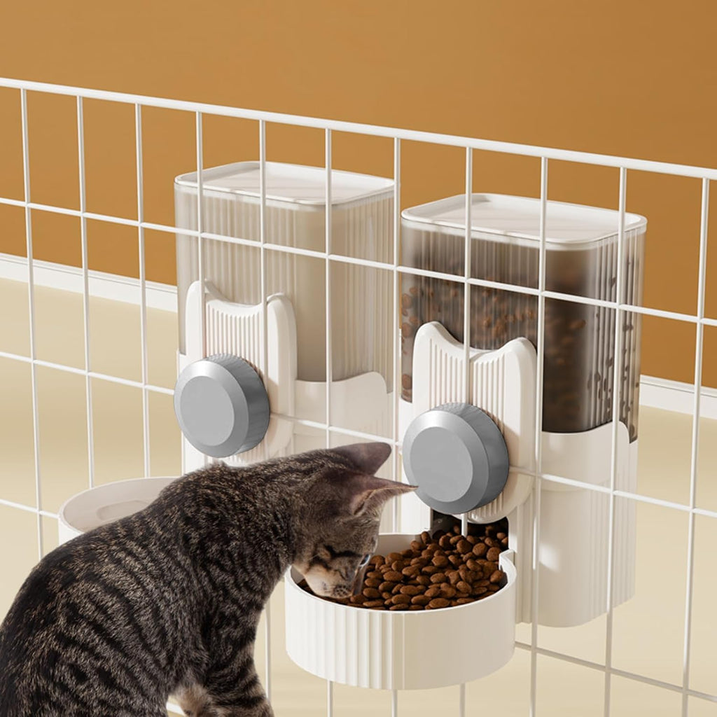 A small kitten eating from the space saving Yummy Sam automatic gravity pet feeder mounted on a white wire kennel.