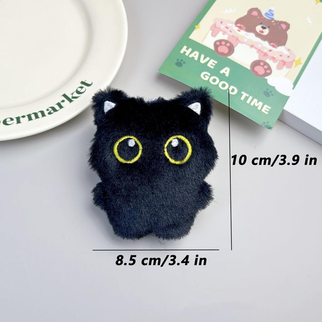 Trio of cute big-eyed black cat plushies displayed together on a flat surface