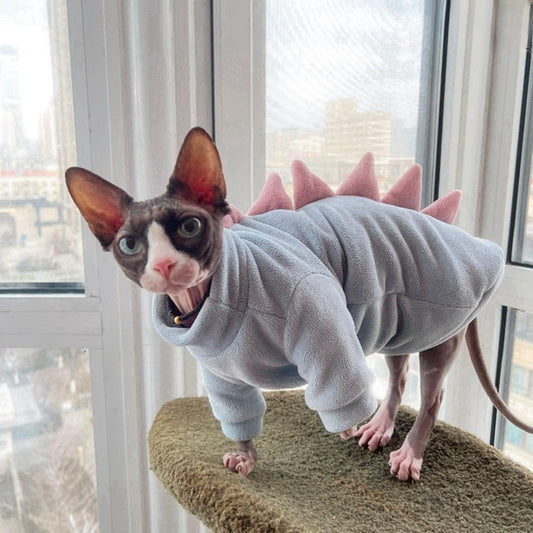 Side view of hairless cat wearing blue dinosaur fleece sweater