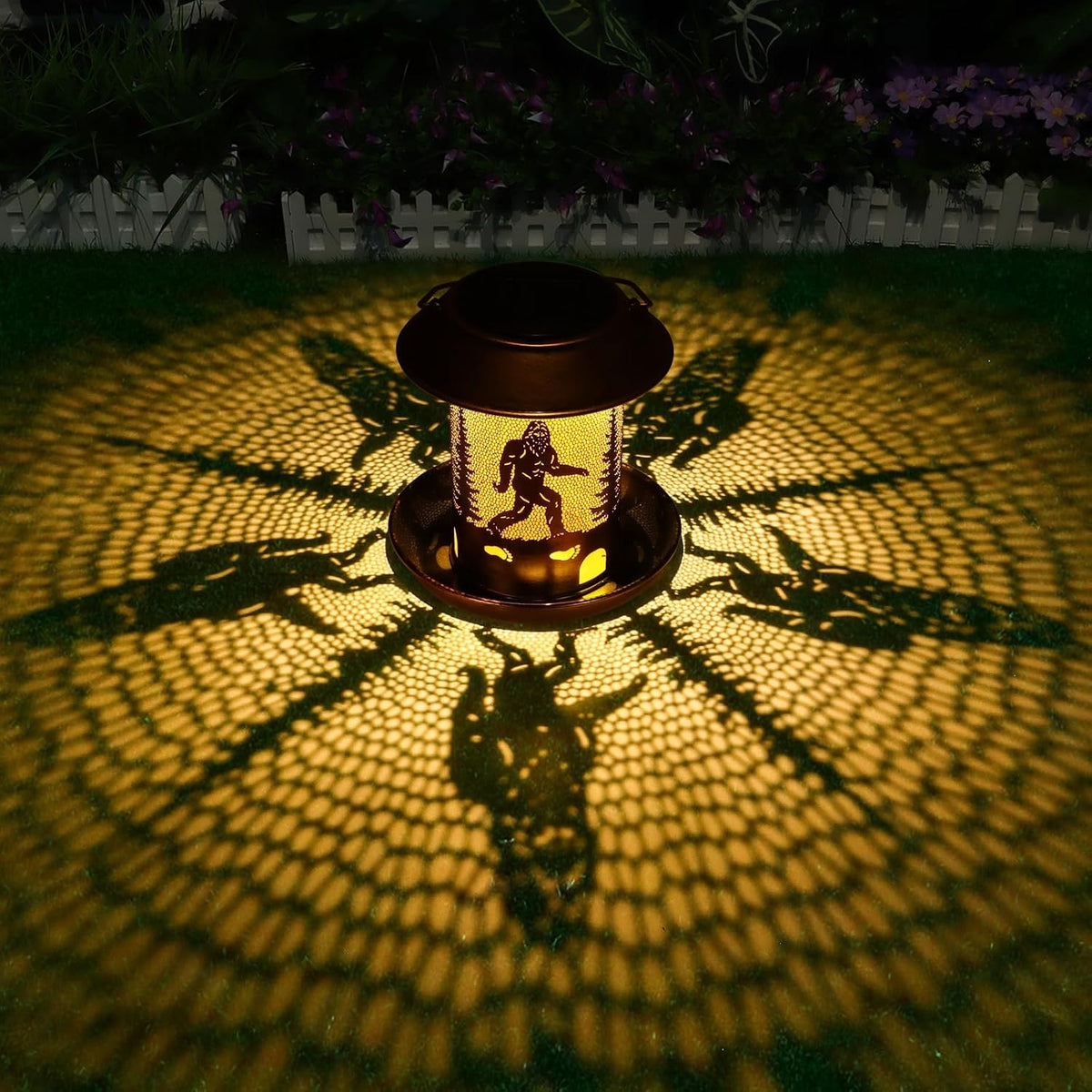 Tepaken hanging metal bird feeder showing glowing Bigfoot forest cutout pattern