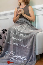 Pawprints Left by You gray plush fleece sympathy throw blanket displayed open on a sofa.