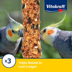 Cockatiel eating Vitakraft Crunch Stick hanging in a bird cage.