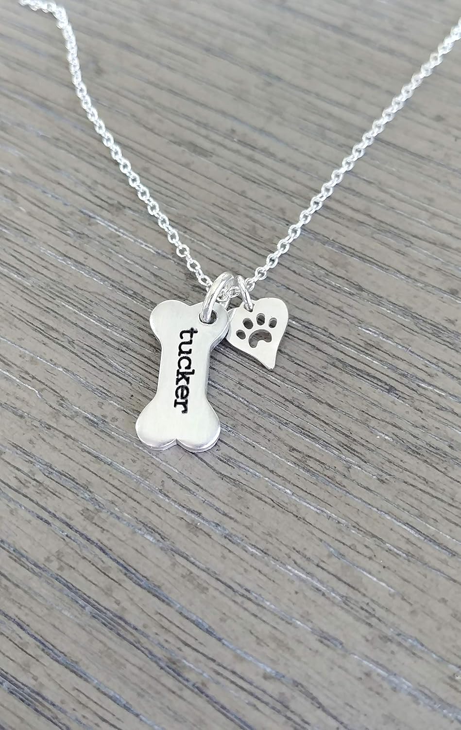 Detailed view of the 12 character engraved dog bone charm on silver chain