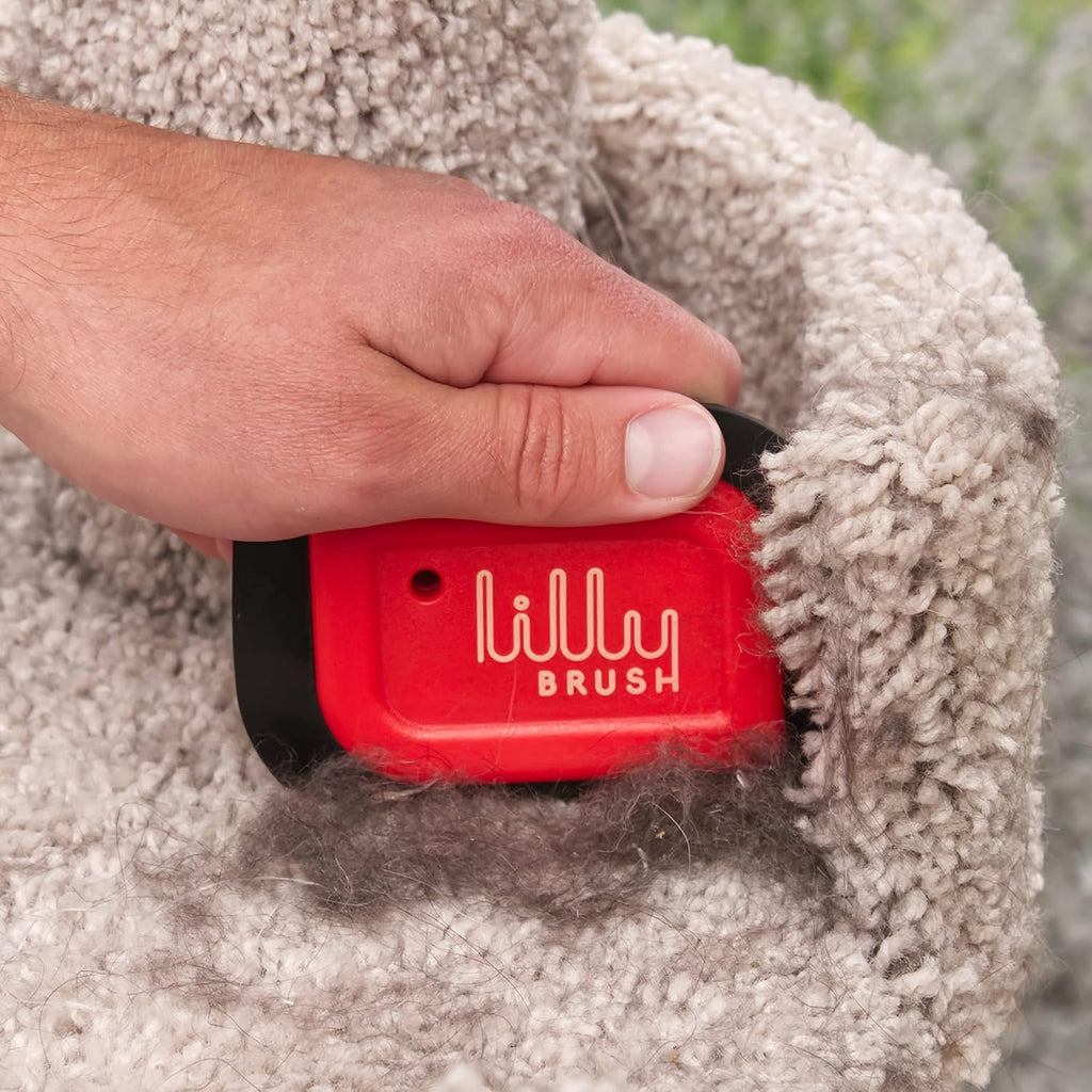 Ergonomic handle design of the red Lilly Brush fur remover held in hand.