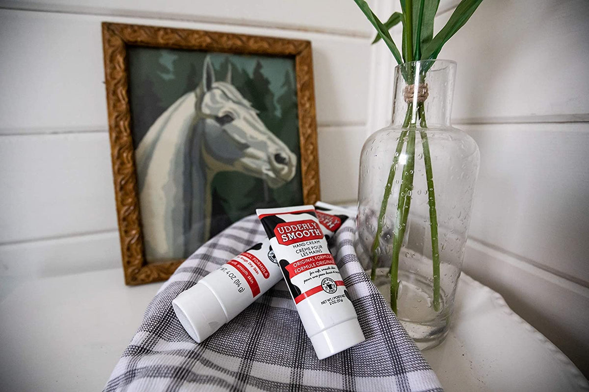 Udderly Smooth Hand Cream travel-friendly four ounce size held in hand for scale