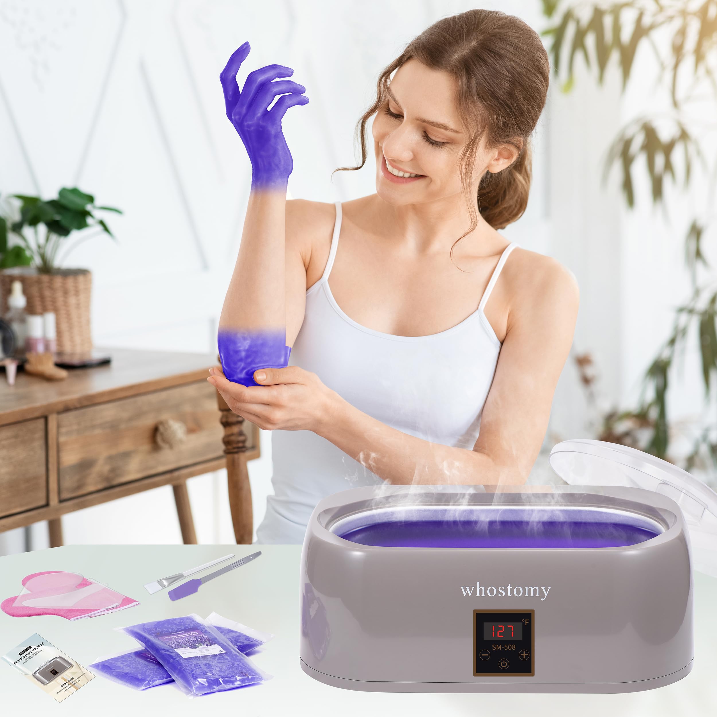 An individual dipping a hand into the warm Whostomy paraffin wax spa machine.