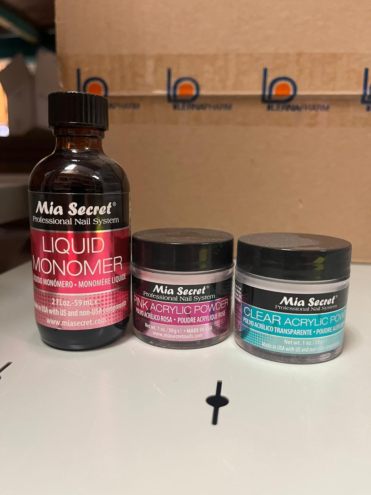 Authentic USA imported Mia Secret clear and pink acrylic polymer powders next to monomer fluid