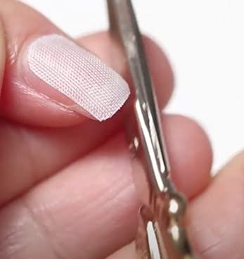 Demonstration of trimming extra wide fiberglass wraps to fit unique nail shapes.