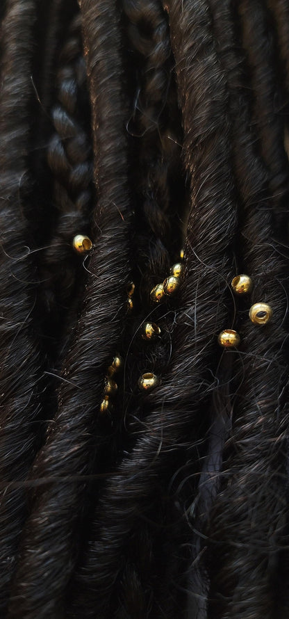 Close up view of sterling silver plated brass 3mm micro hair jewelry pieces on a plain background