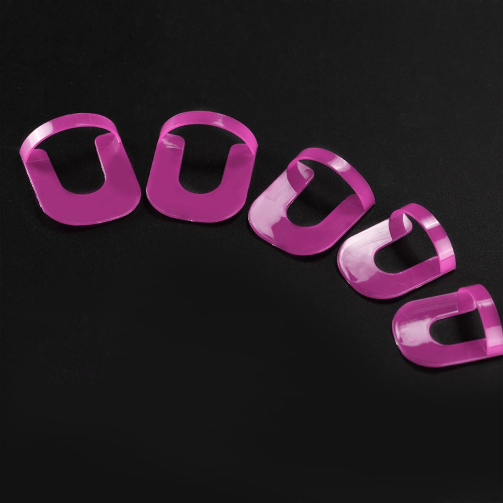 Close up view of a hand wearing the flexible spill proof manicure guards around the cuticles during nail polish application.