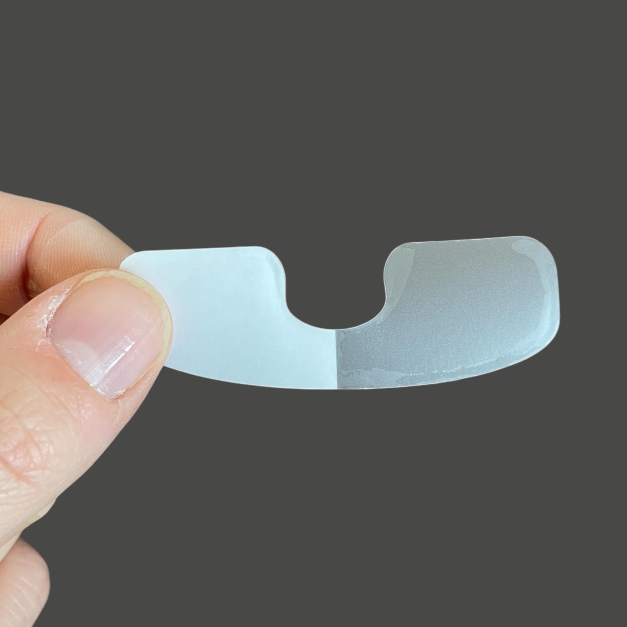 Close up of a human finger wearing the invisible Chalmery cuticle protector patch