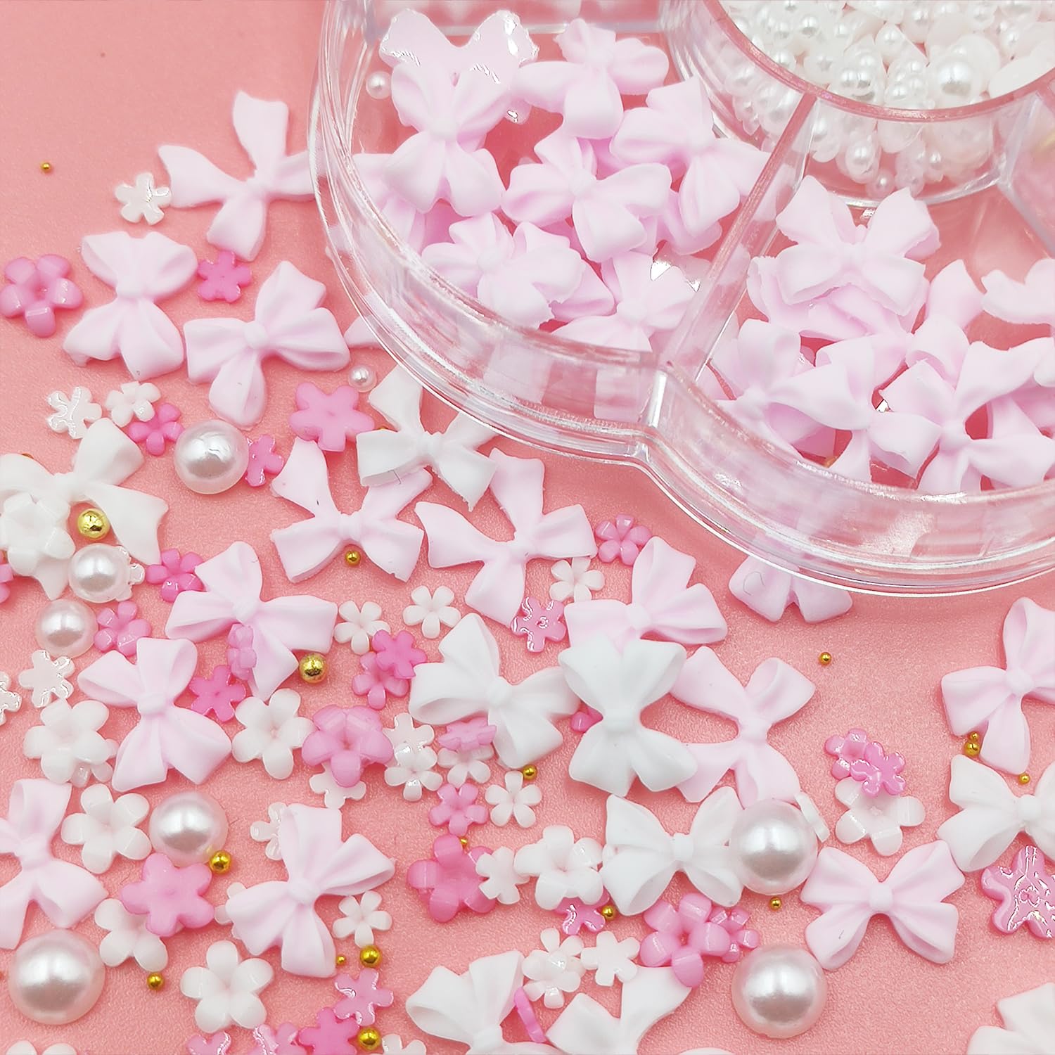 A variety of white half pearls and floral acrylic gems displayed next to manicure tools.