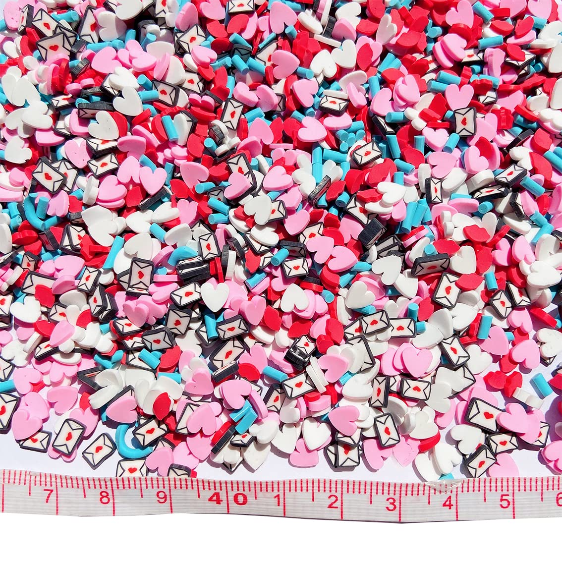 Overhead view of 50 grams package of Valentine themed faux candy sprinkles scattered on a white background