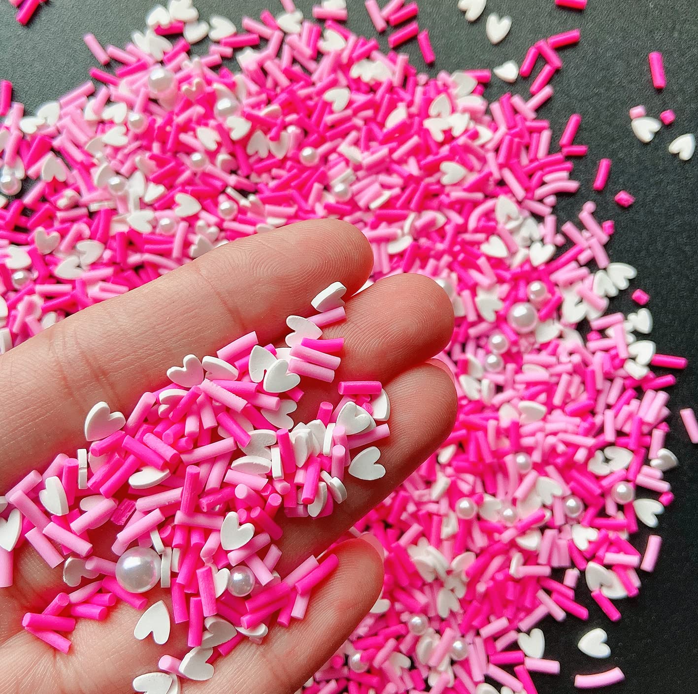 Close up view of pink heart polymer clay slices and white resin pearls