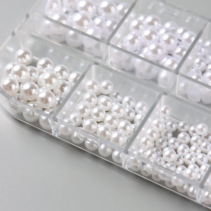Various sizes of white nail pearls displayed on a surface
