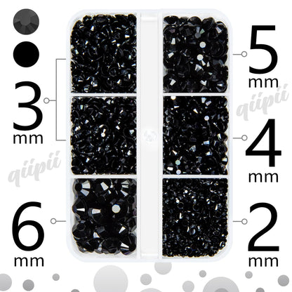 Hand holding tweezers applying black resin gems to nail art