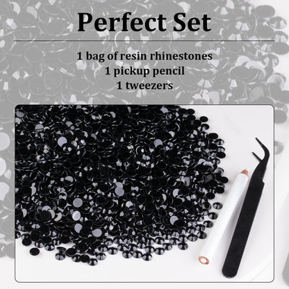 Hand holding wax pickup pencil applying black resin gems to nails