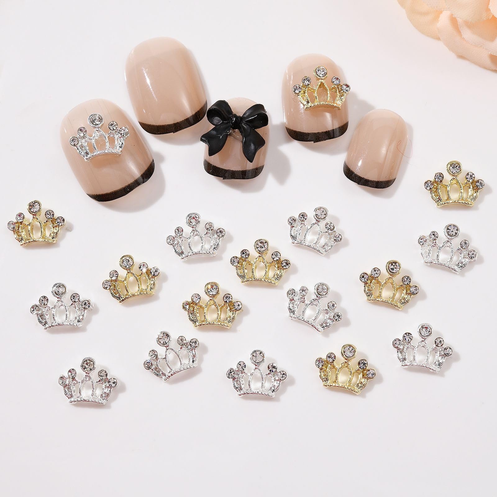 Flatback alloy bow charms being applied with tweezers onto a fresh gel manicure.