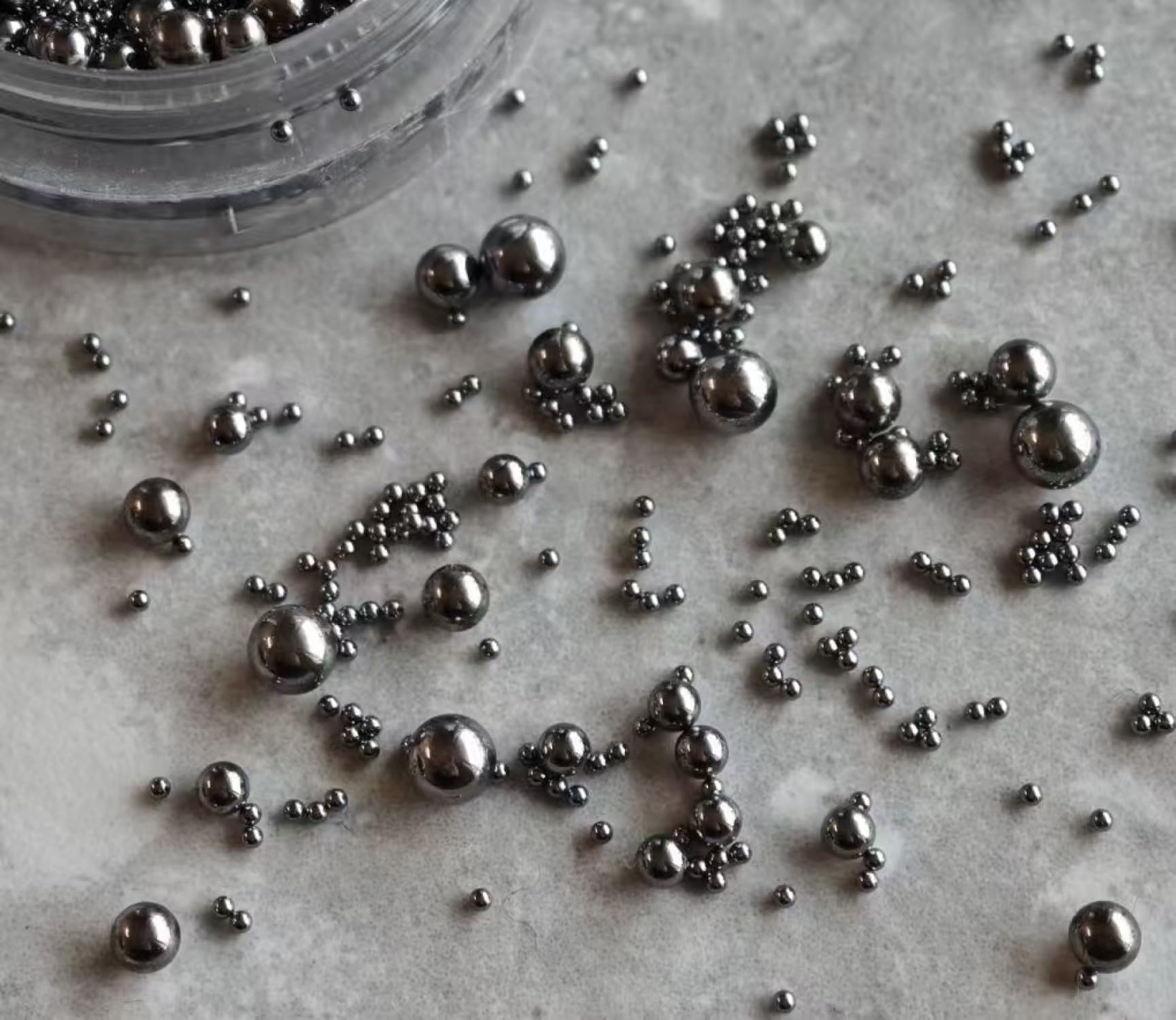 Close up of mixed size metallic mini nail ball beads ranging from point four to three millimeters for intricate manicure designs