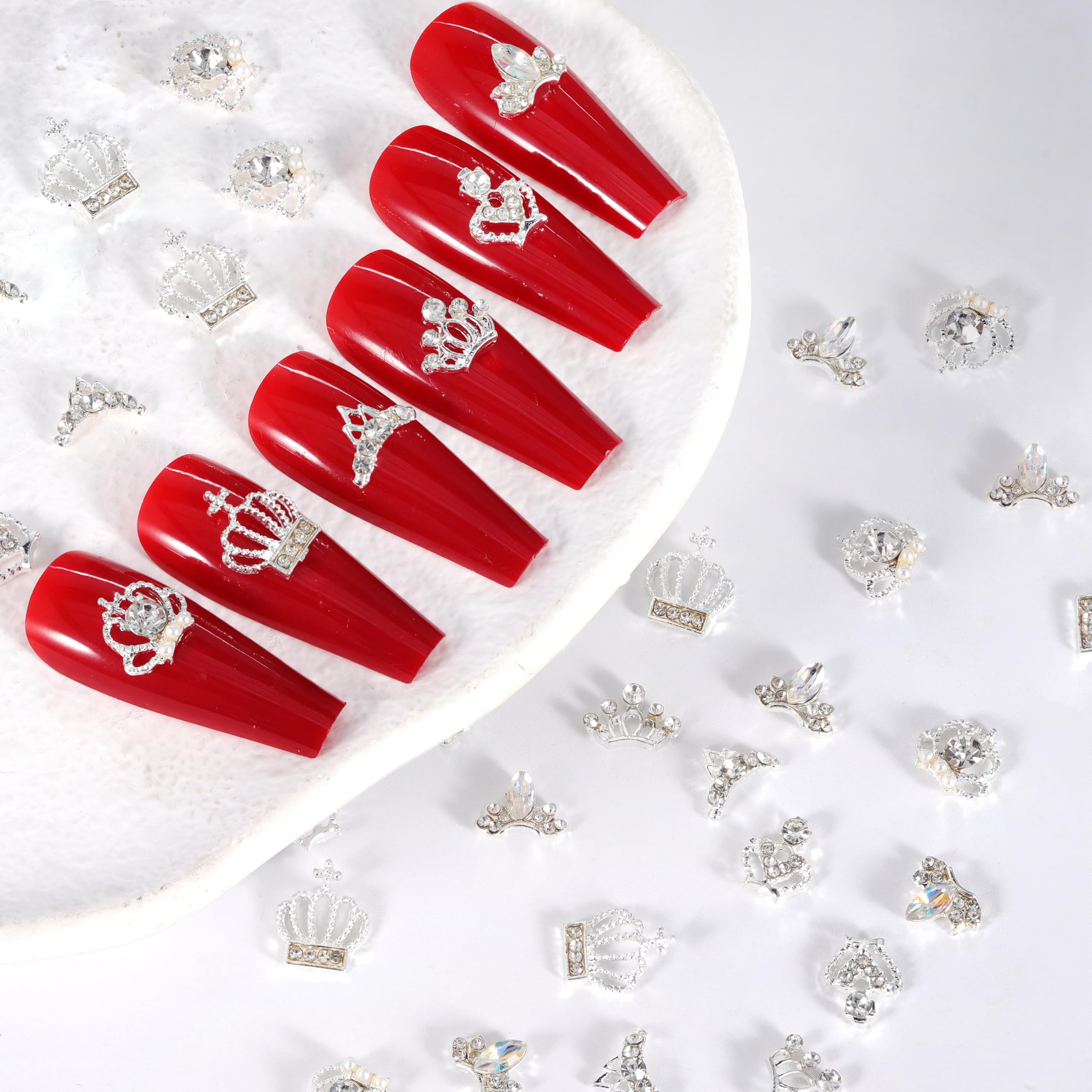 Silver alloy crown nail charms being positioned on a nail using the included application tweezers.