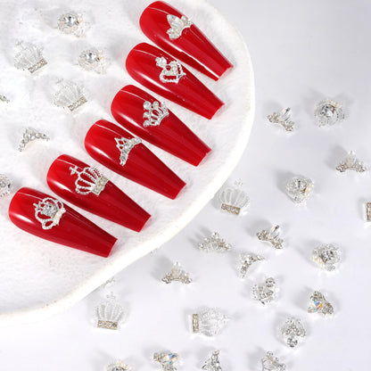 Silver alloy crown nail charms being positioned on a nail using the included application tweezers.