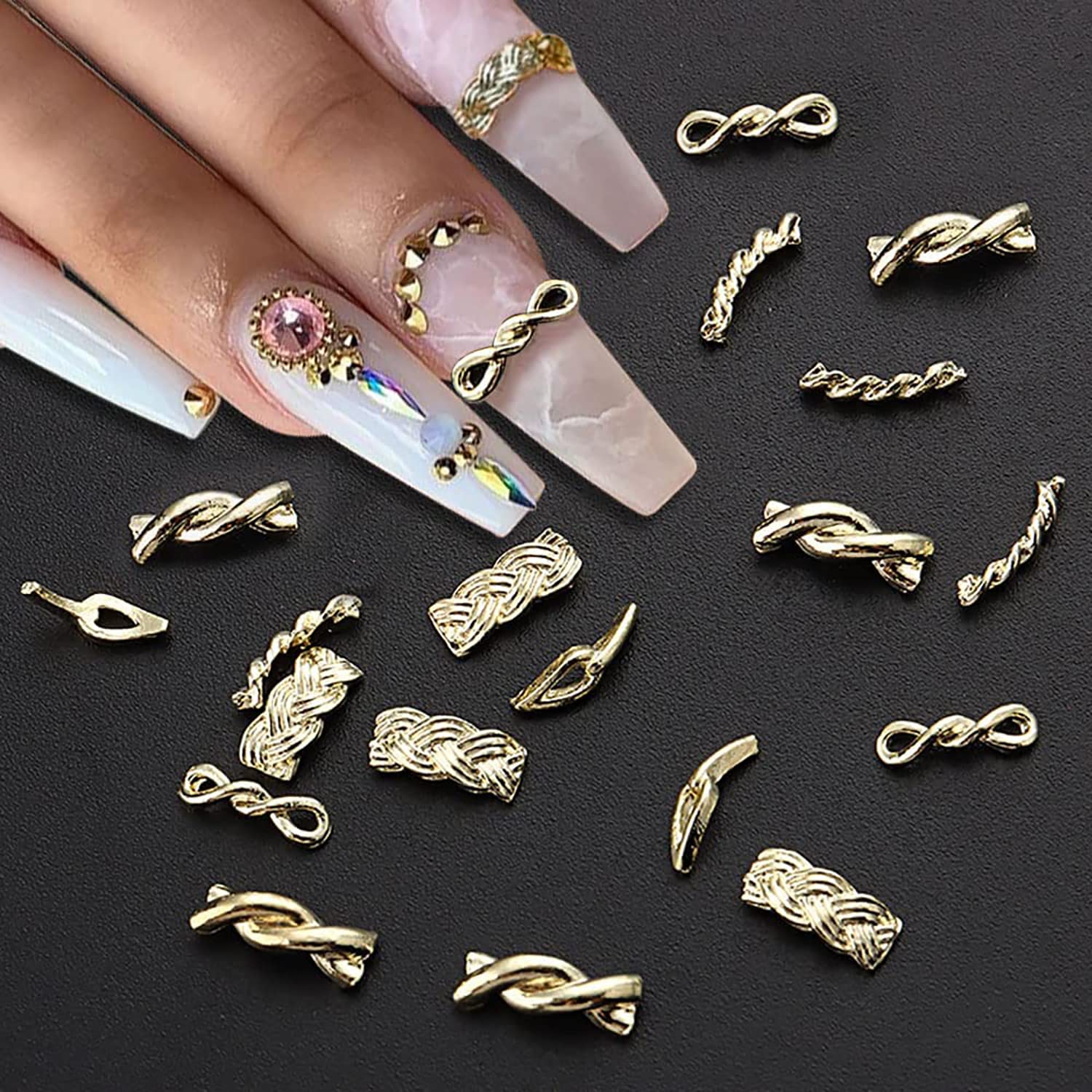 Close up view of gold alloy snake shaped and rope knot nail ornaments laid out on a professional workstation.