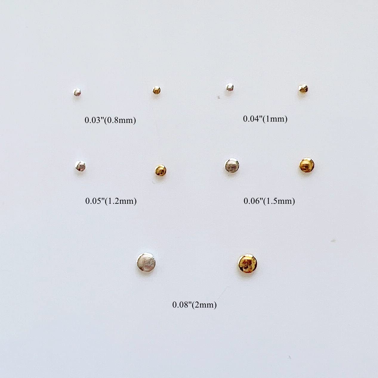 Close up view of miniature gold nail embellishments in various millimeter sizes on a flat surface.