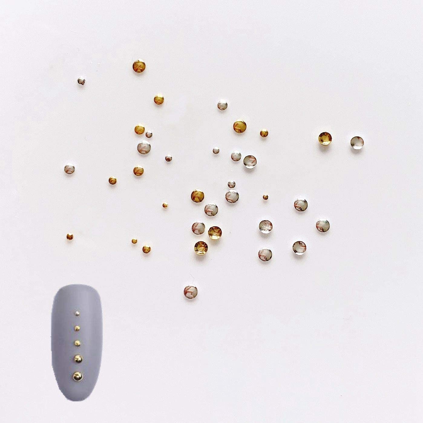 Demonstration of mixing multi size metallic nail accents to create intricate patterns on manicured fingertips.