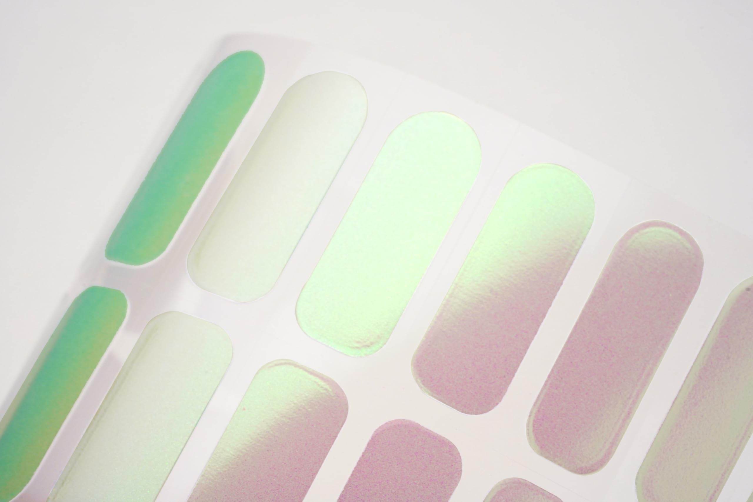 Hands applying iridescent gel nail stickers at home