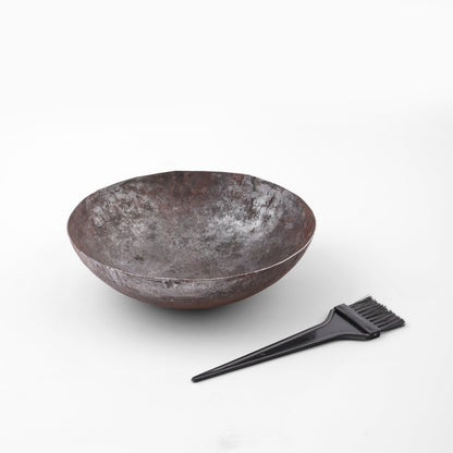 Black plastic hair dye brush resting on pure solid iron bowl