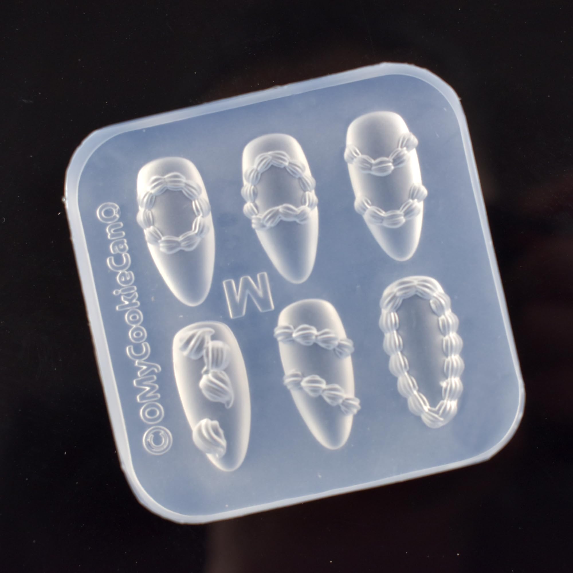 Lifoost 3D carving template showing flexible silicone material being bent to release cured resin charms.